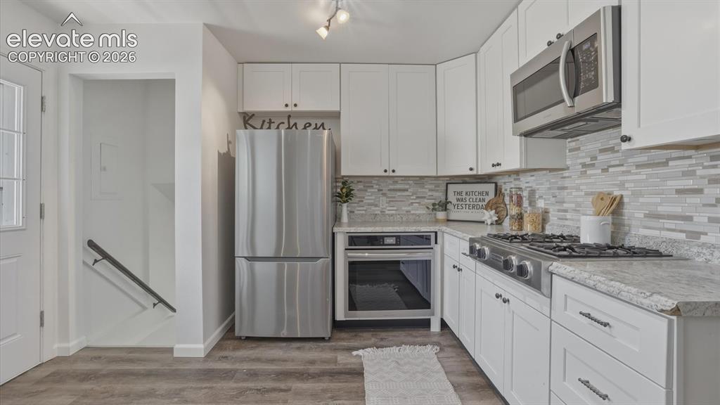 Image 24 of 48: The updated Kitchen boasts white cabinetry, granite countertops, tile backs