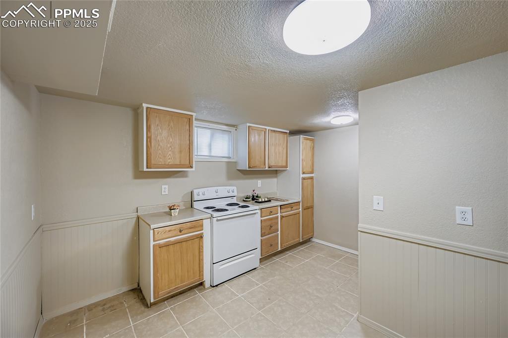 Image 14 of 25: Kitchen with electric stove, light countertops, a textured ceiling, a wains