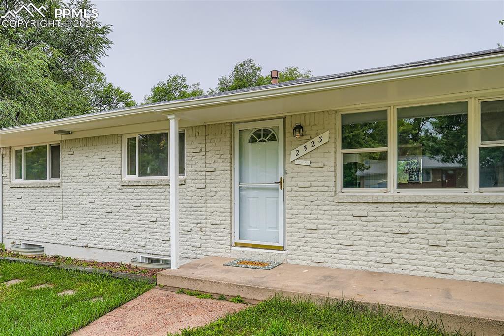 Image 23 of 25: Property entrance with brick siding and a porch