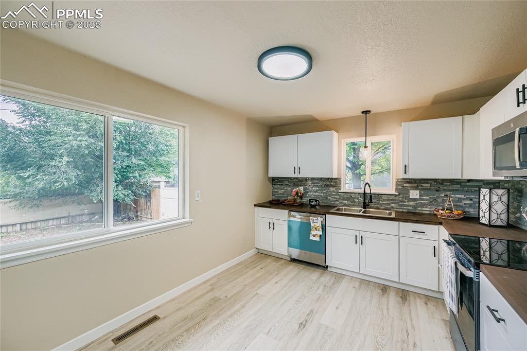 Image 5 of 25: Kitchen featuring stainless steel appliances, hanging light fixtures, white