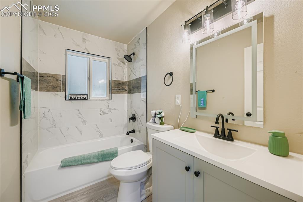 Image 6 of 25: Bathroom with  shower combination, vanity, wood finished floors, and a text