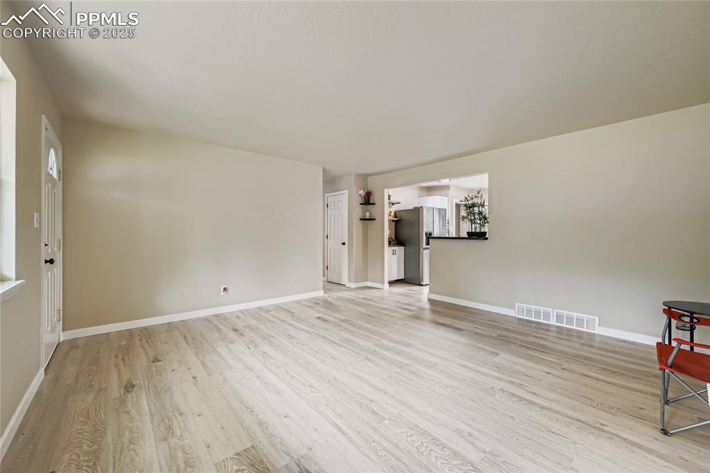 Image 9 of 25: Unfurnished living room with light wood finished floors and baseboards