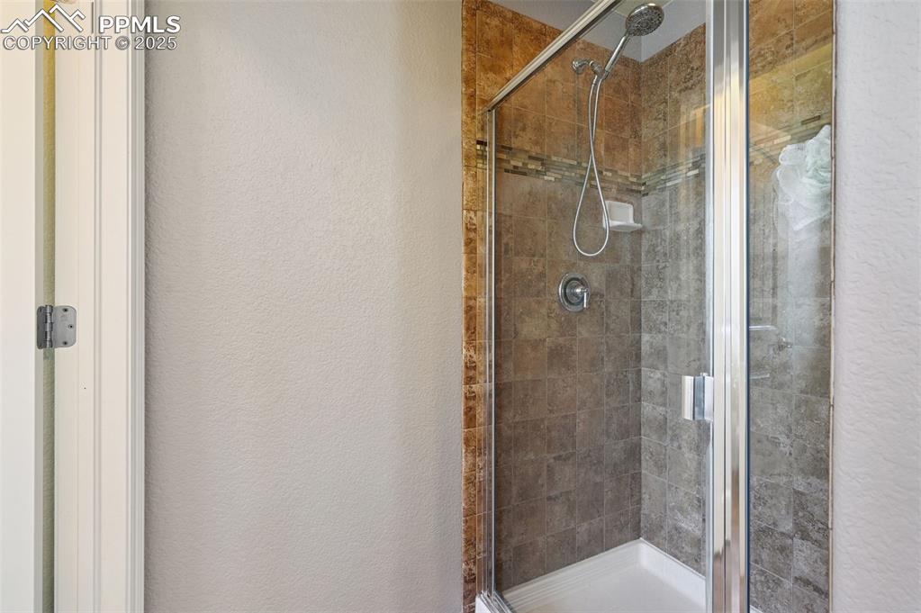Image 16 of 39: Bathroom featuring a textured wall and a stall shower
