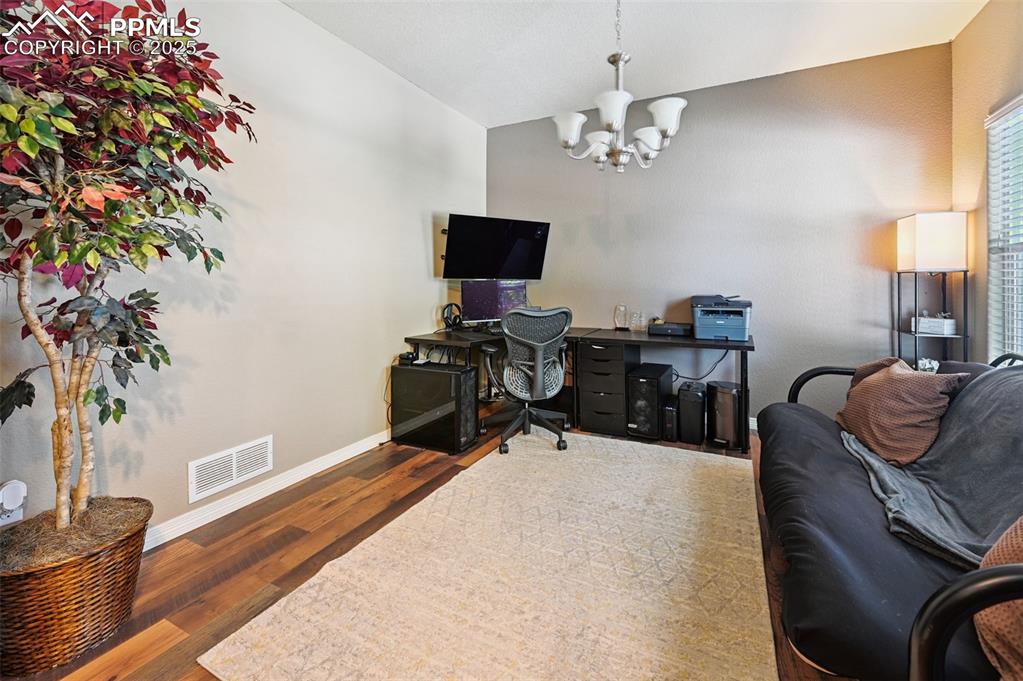 Image 19 of 39: Home office featuring wood finished floors, a chandelier, and lofted ceilin