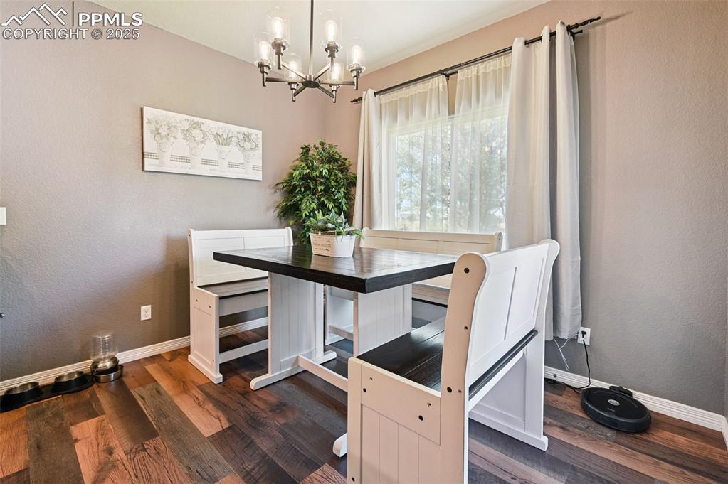 Image 22 of 39: Dining room featuring a textured wall, dark wood-type flooring, and a chand