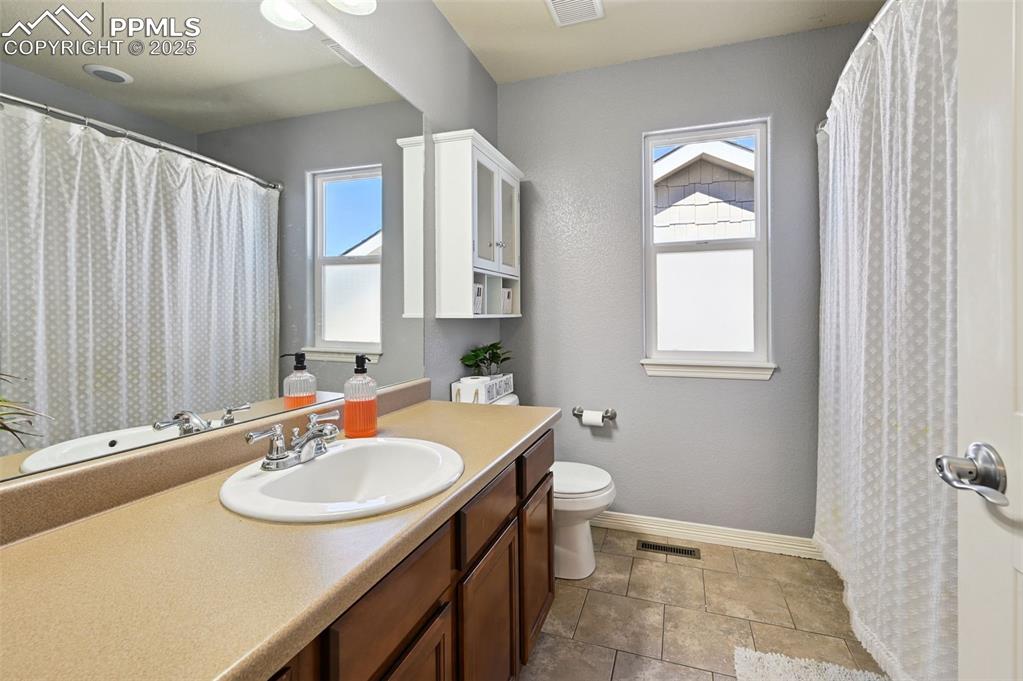 Image 26 of 39: Full bathroom with healthy amount of natural light, vanity, and a shower wi