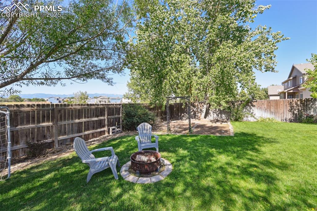 Image 3 of 39: Fenced backyard with an outdoor fire pit and a patio area