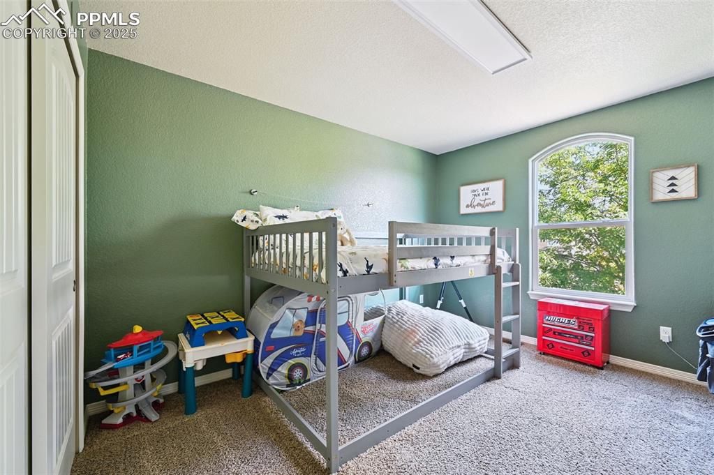 Image 33 of 39: Bedroom featuring a textured wall, a closet, carpet floors, and a textured 