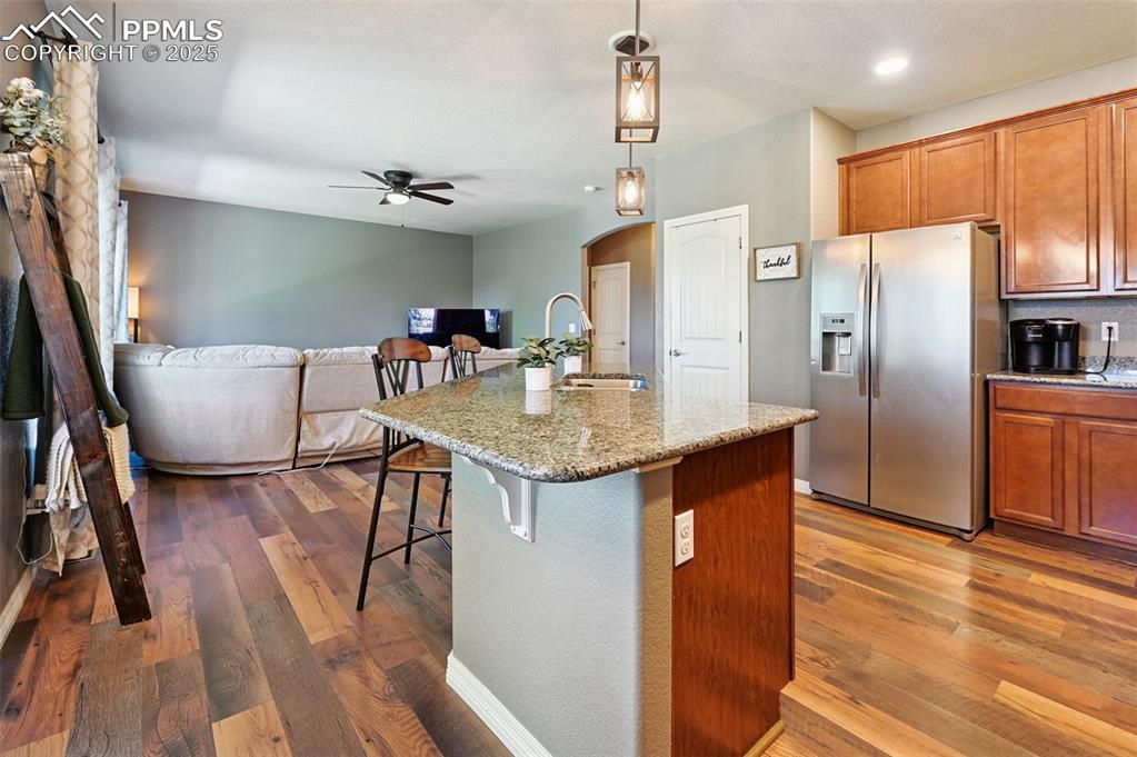Image 7 of 39: Kitchen with stainless steel fridge, arched walkways, brown cabinetry, a ki