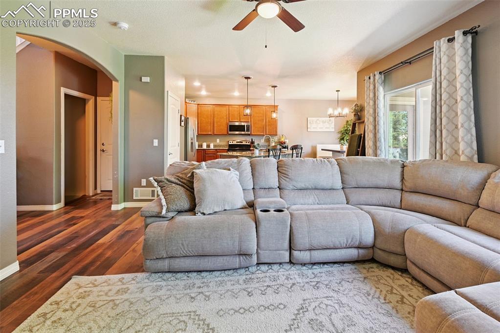 Image 9 of 39: Living room featuring a ceiling fan, dark wood-style floors, arched walkway