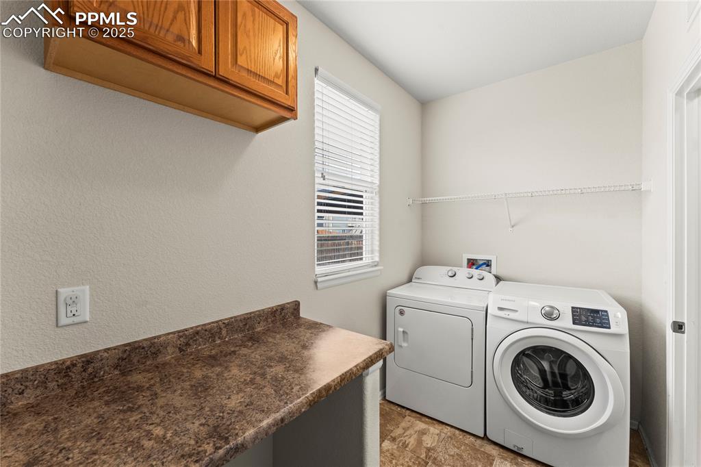 Image 16 of 39: Washroom with washer and dryer and light stone finish flooring