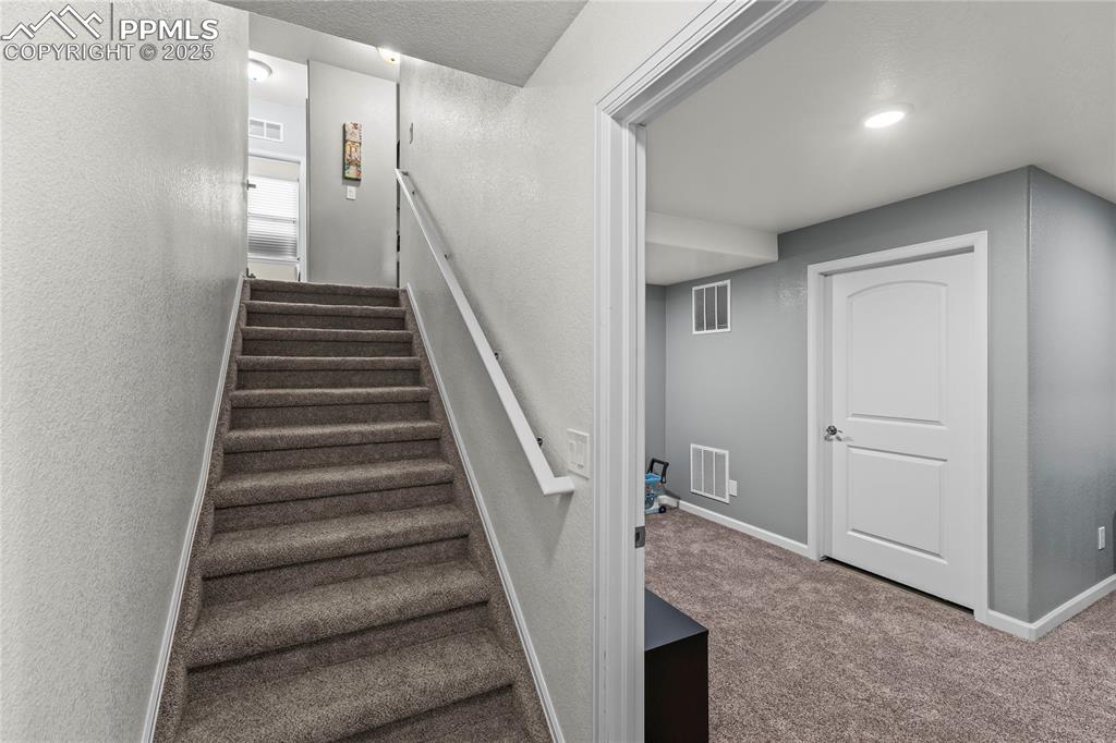 Image 17 of 39: Stairway with a textured wall and carpet