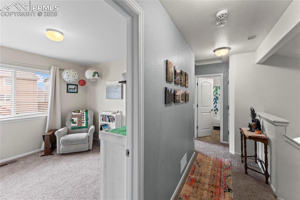 Image 25 of 39: Hallway featuring light carpet, a textured ceiling, and a textured wall