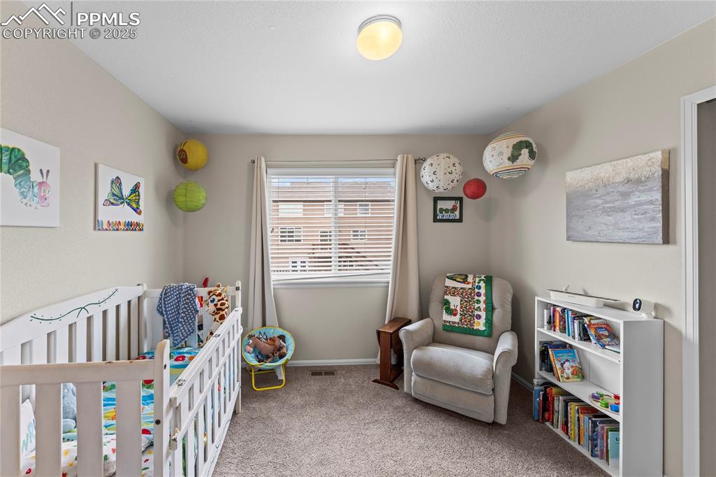 Image 26 of 39: Bedroom featuring a crib and light colored carpet