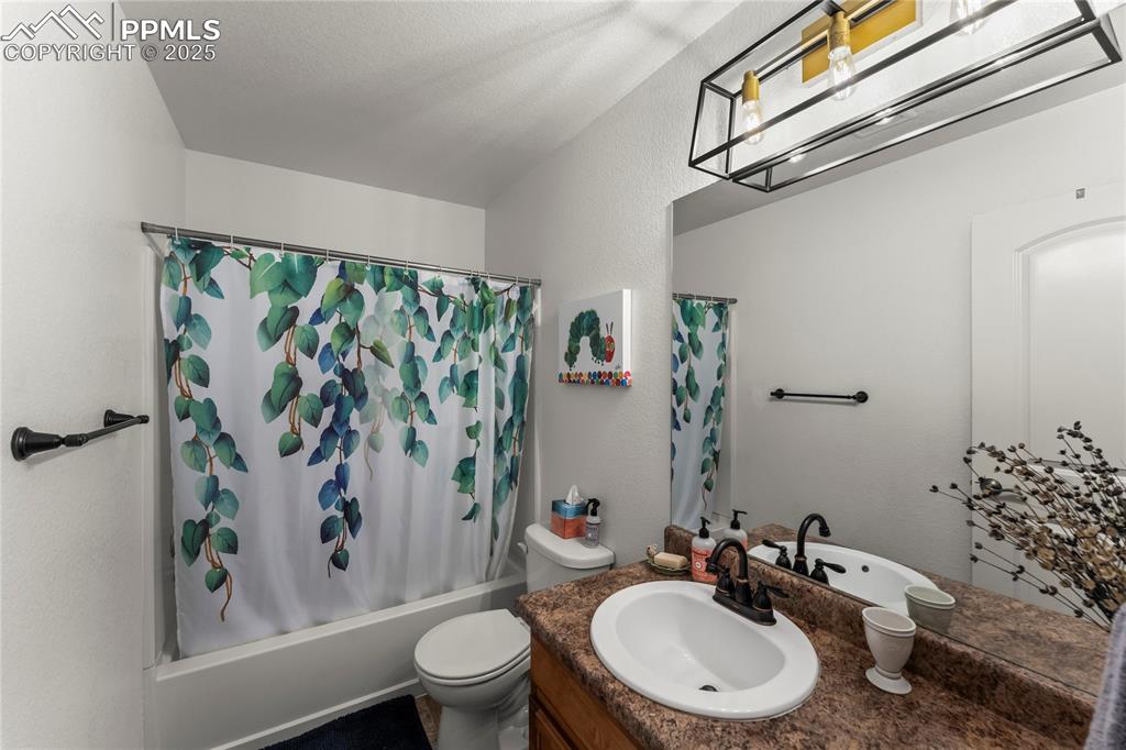 Image 28 of 39: Full bathroom with shower / tub combo, a textured wall, and vanity