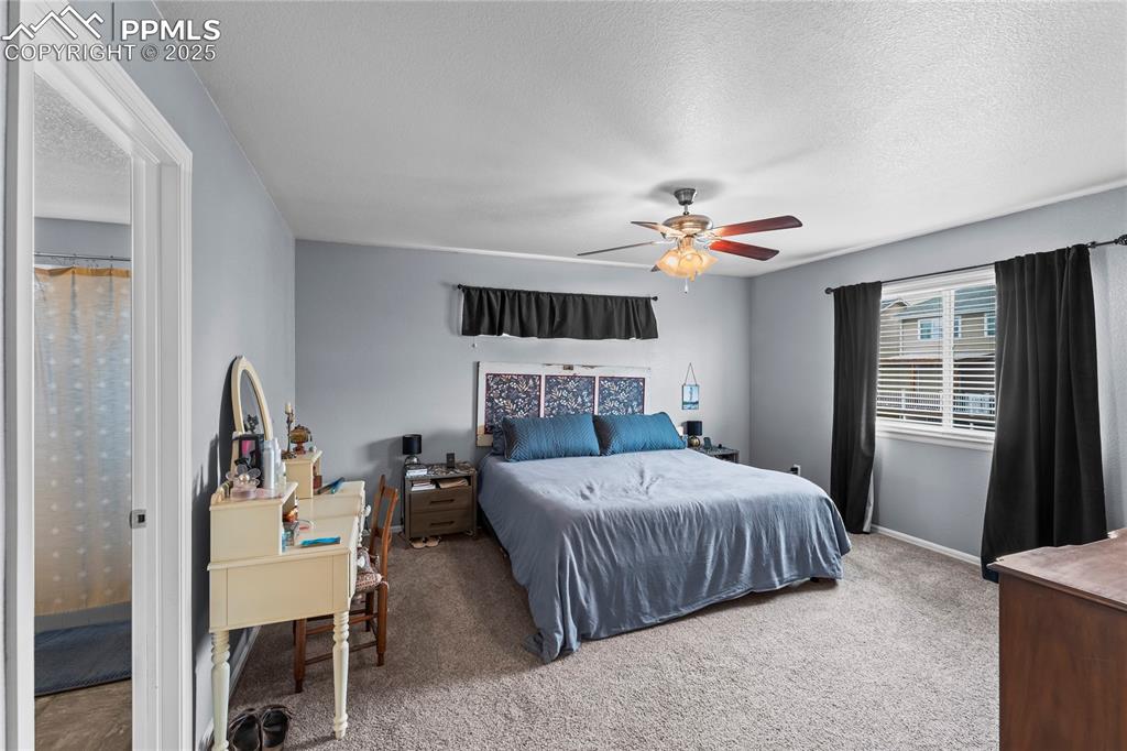 Image 31 of 39: Bedroom with carpet, ceiling fan, and a textured ceiling