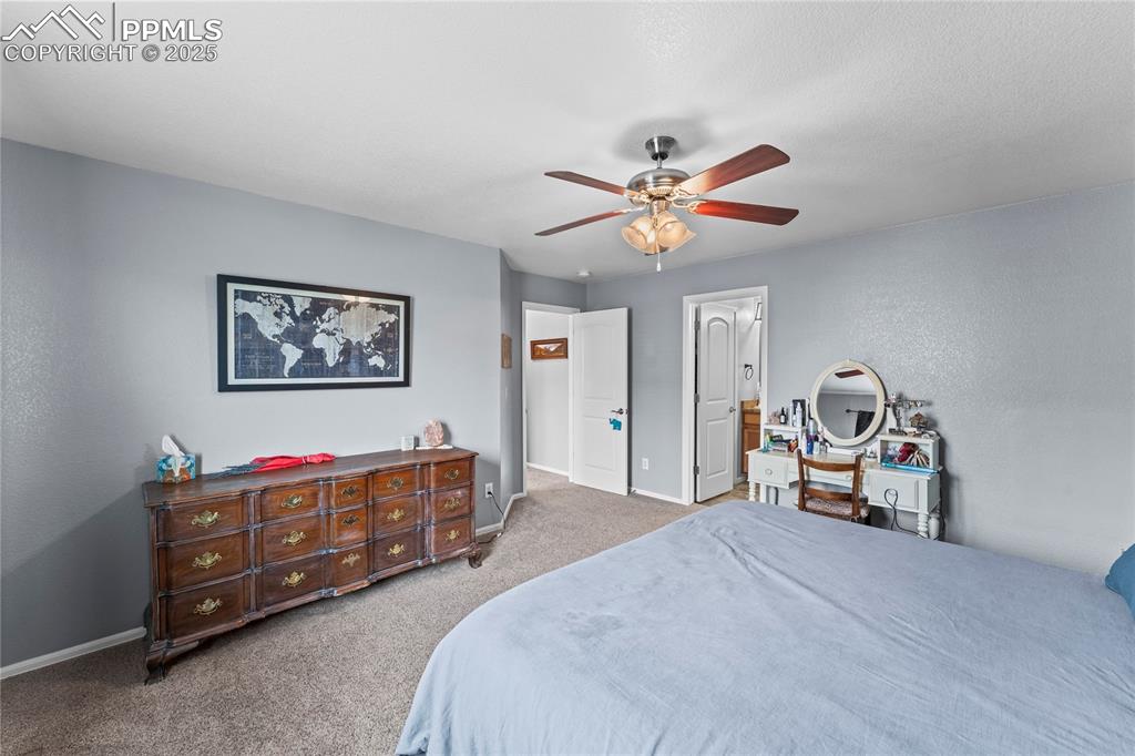 Image 32 of 39: Bedroom with light colored carpet, a ceiling fan, connected bathroom, and a