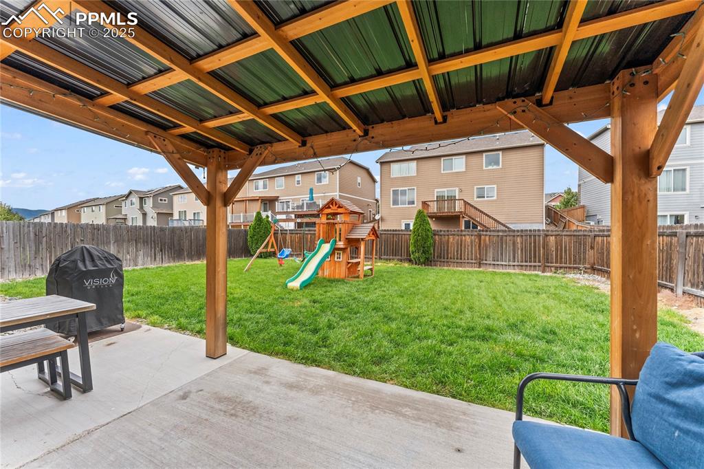 Image 34 of 39: Fenced backyard with a residential view, a patio, and a playground
