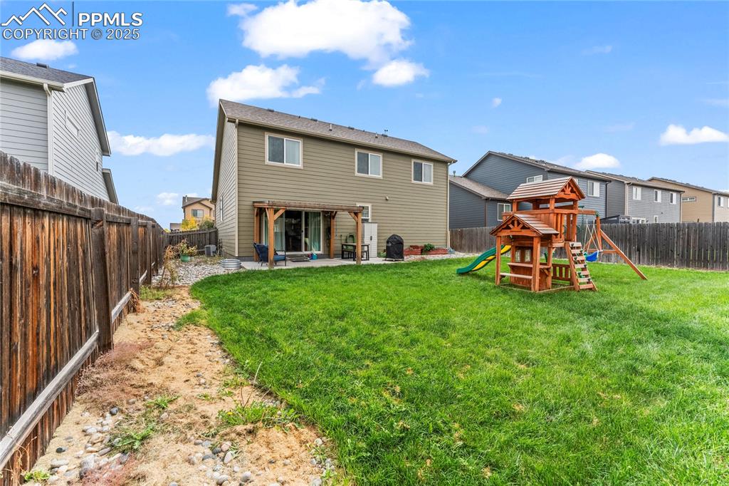 Image 35 of 39: Rear view of house featuring a fenced backyard, a patio, and a playground