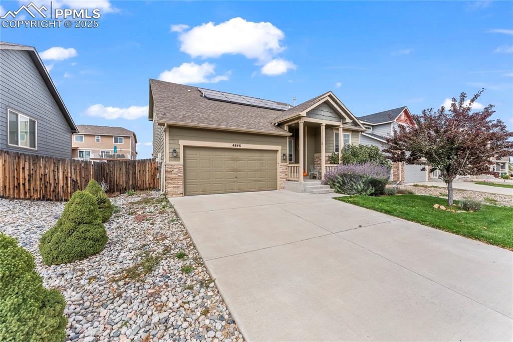 Image 38 of 39: View of front of property featuring a shingled roof, stone siding, solar pa