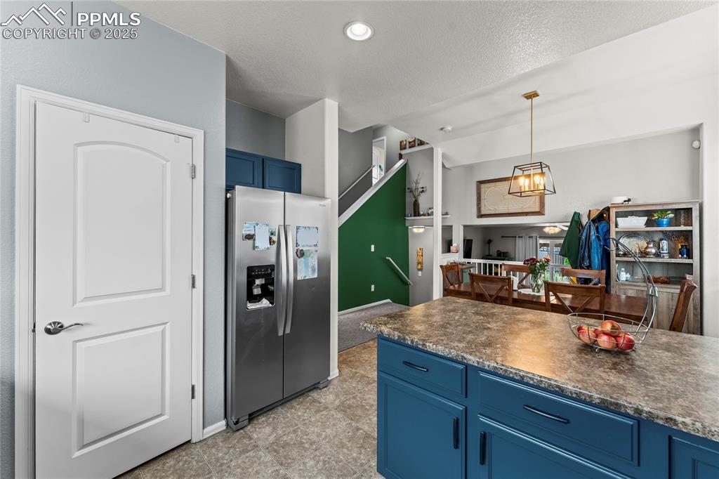 Image 4 of 39: Kitchen featuring blue cabinets, stainless steel fridge with ice dispenser,