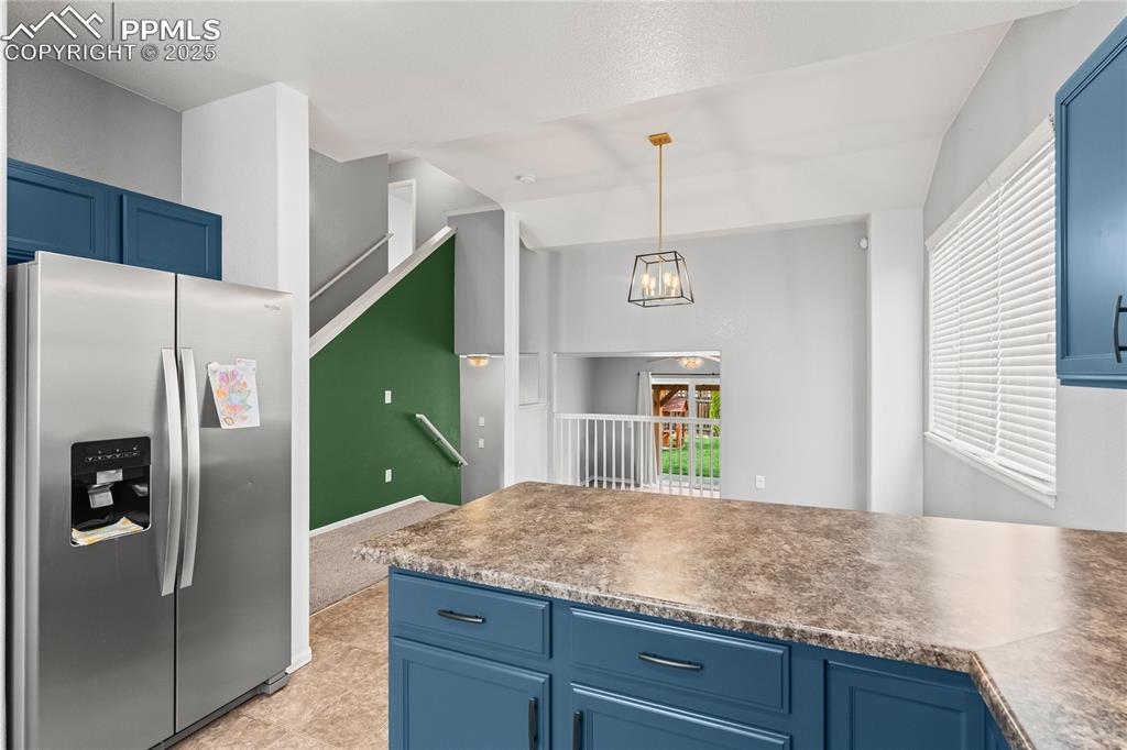 Image 5 of 39: Kitchen featuring blue cabinetry, stainless steel fridge with ice dispenser