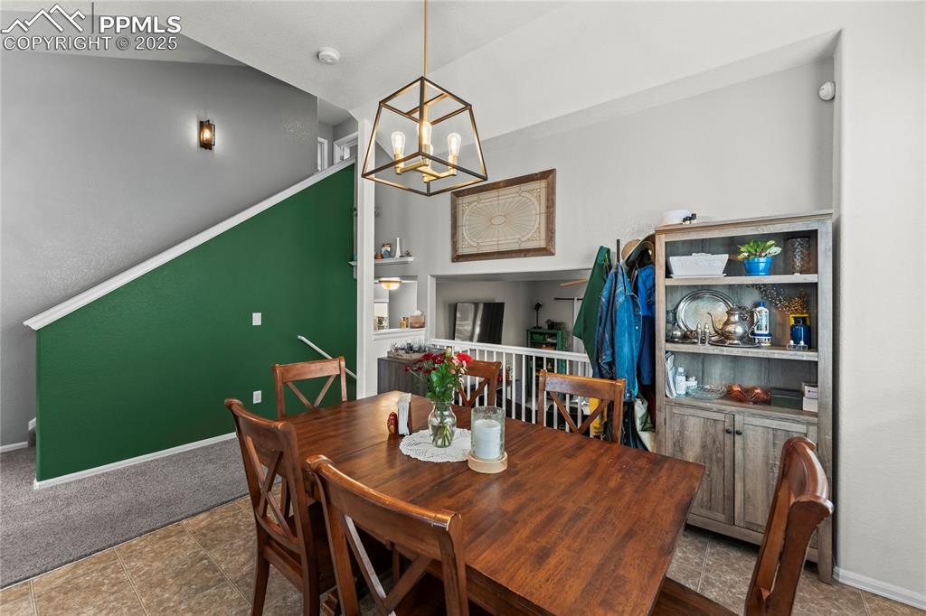 Image 6 of 39: Dining space with vaulted ceiling, a chandelier, and built in shelves