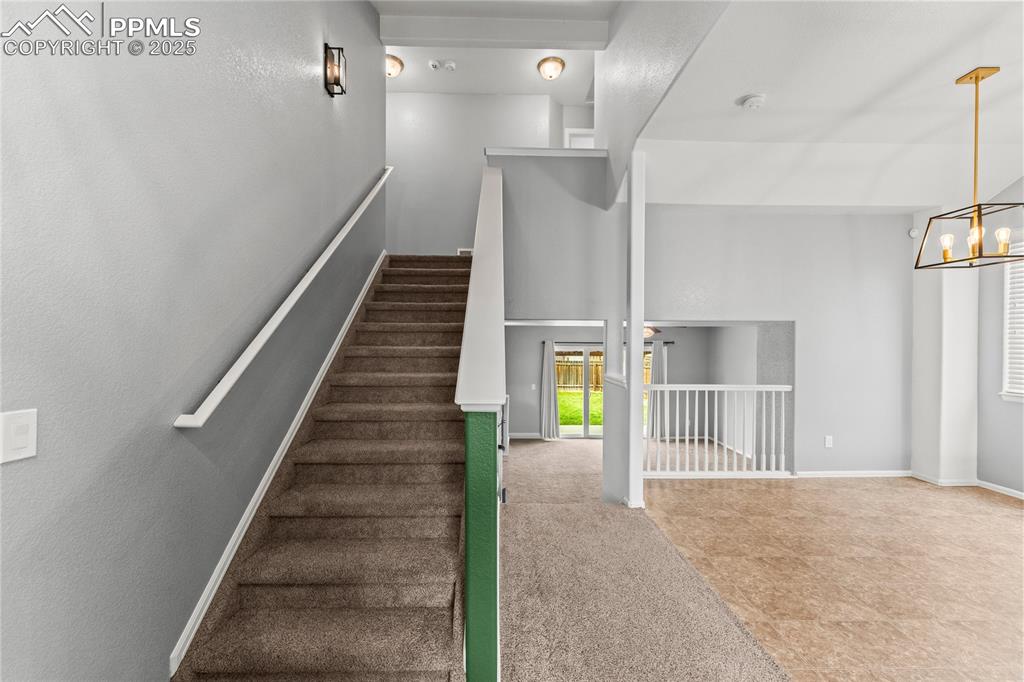 Image 8 of 39: Stairs with carpet floors, a chandelier, and a towering ceiling