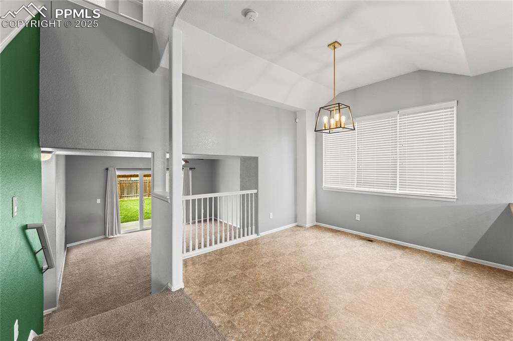 Image 9 of 39: Spare room with lofted ceiling and a chandelier