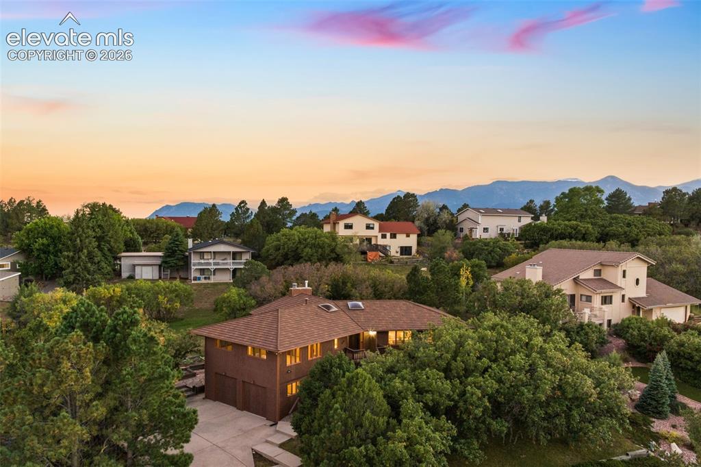 Image 1 of 50: Wood-sided residence with an attached garage, surrounded by mature trees, a