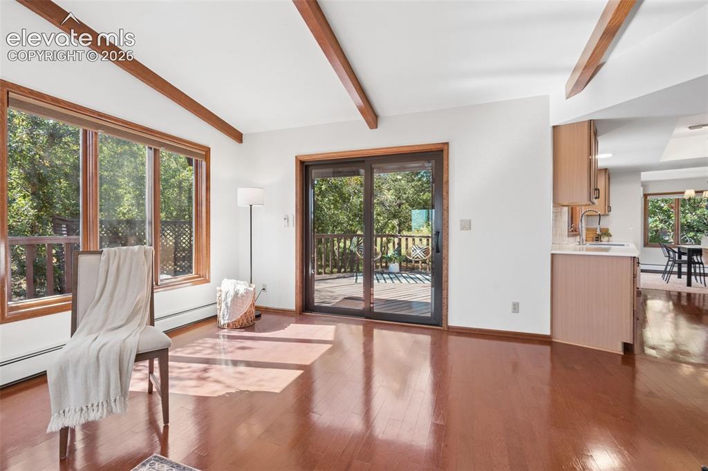 Image 10 of 50: Warm wood-finish flooring, exposed ceiling beams, large picture windows, an