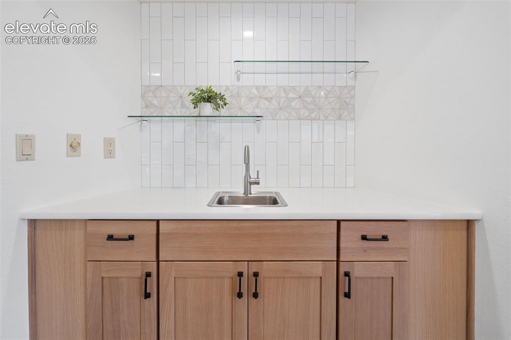 Image 11 of 50: Wood-finish cabinetry with black hardware, white countertop, stainless stee