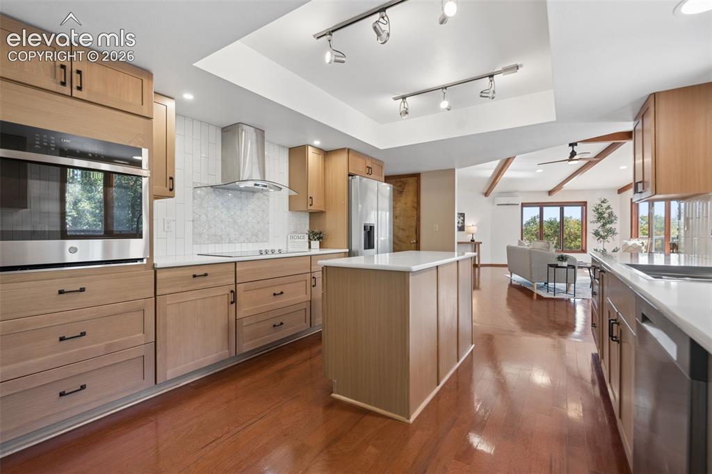 Image 12 of 50: Light wood-finish cabinetry, stainless steel appliances, white countertops,