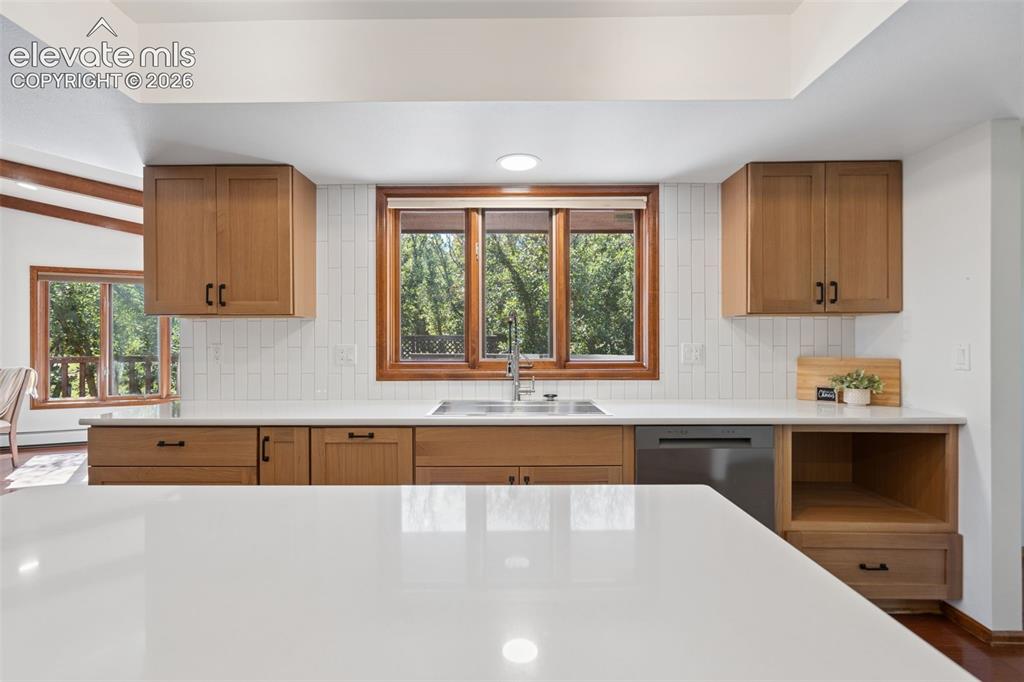 Image 14 of 50: Kitchen featuring solid surface countertops, wood cabinetry, a stainless st
