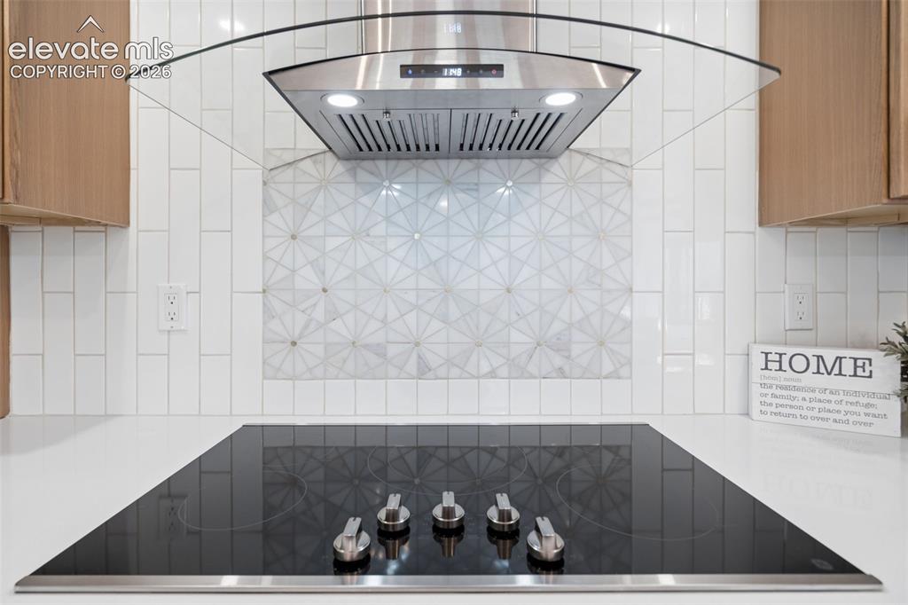 Image 15 of 50: Integrated cooktop with stainless steel controls, white countertop, white v