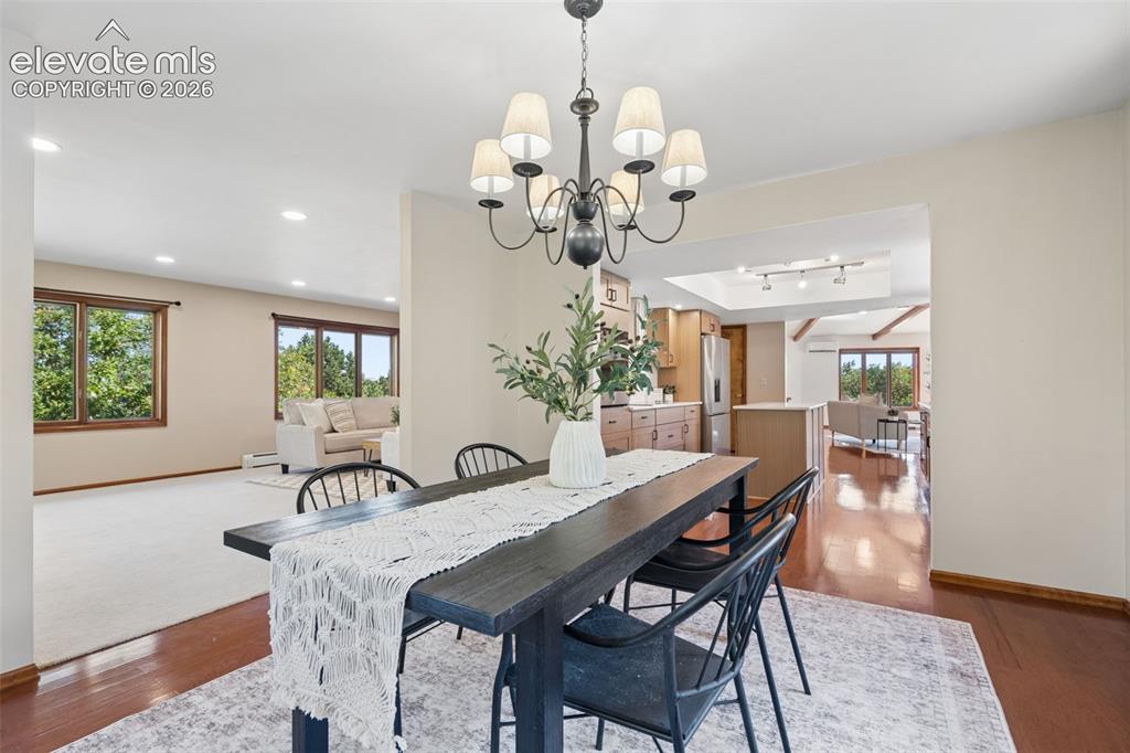 Image 18 of 50: Recessed lighting, wood-finish flooring, and a chandelier with fabric shade