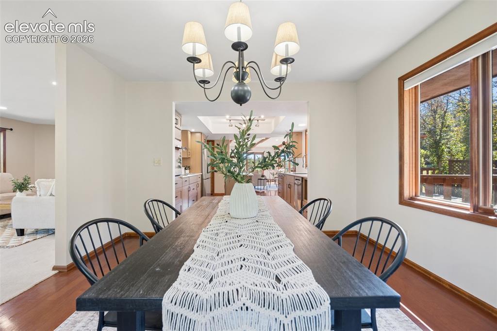 Image 19 of 50: Hardwood flooring, a five-light chandelier, and a wood-framed window
