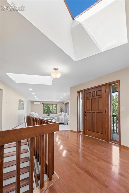 Image 22 of 50: Hardwood flooring throughout, a paneled wood entry door, and multiple skyli