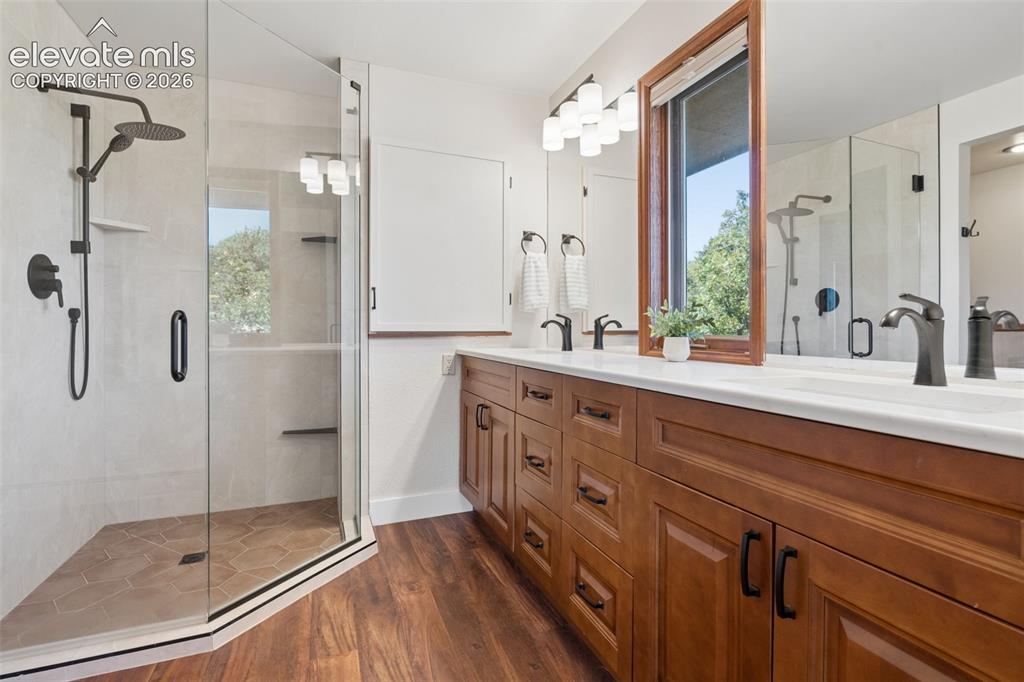 Image 28 of 50: Glass-enclosed shower with a rainfall showerhead, integrated shelving, and