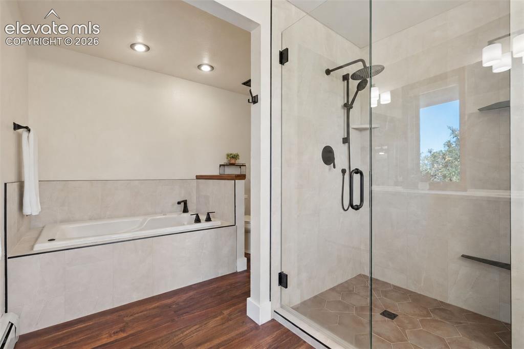 Image 29 of 50: Glass-enclosed shower with matte black fixtures, an integrated tub, and woo