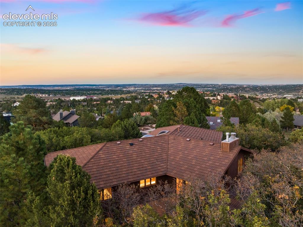 Image 3 of 50: Wood-shingle roofline property surrounded by mature trees, with a broad exp
