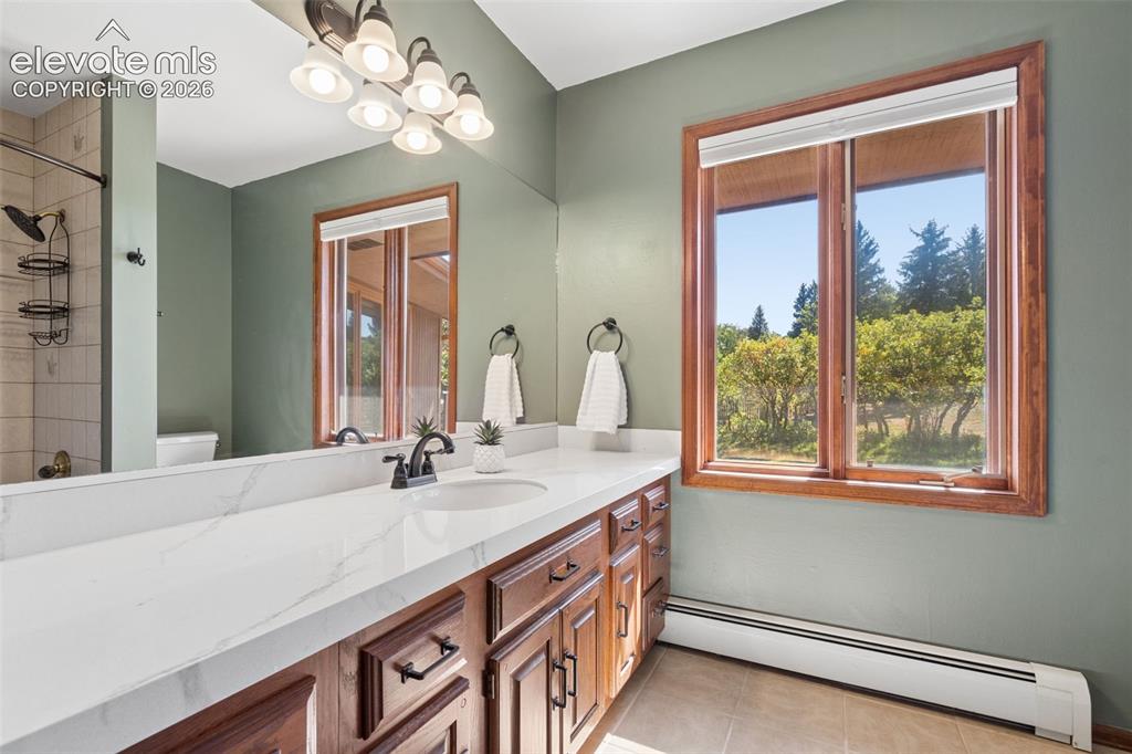 Image 31 of 50: Dual basin vanity with a light-toned countertop, wood-finish cabinetry, and