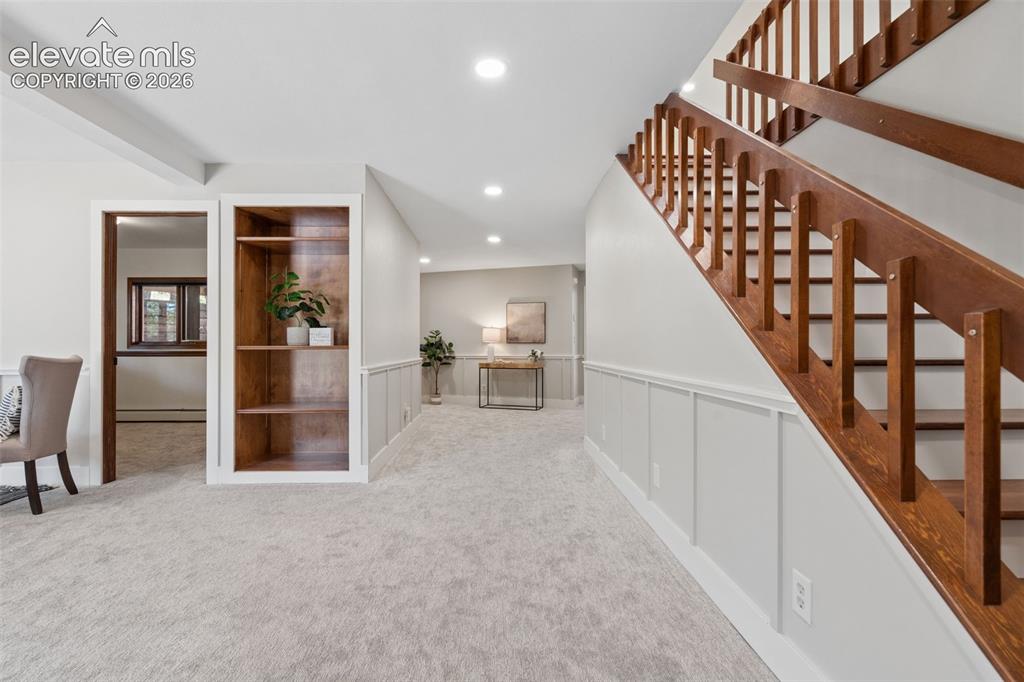Image 33 of 50: Wood staircase with vertical balusters, light gray wall paneling, built-in 
