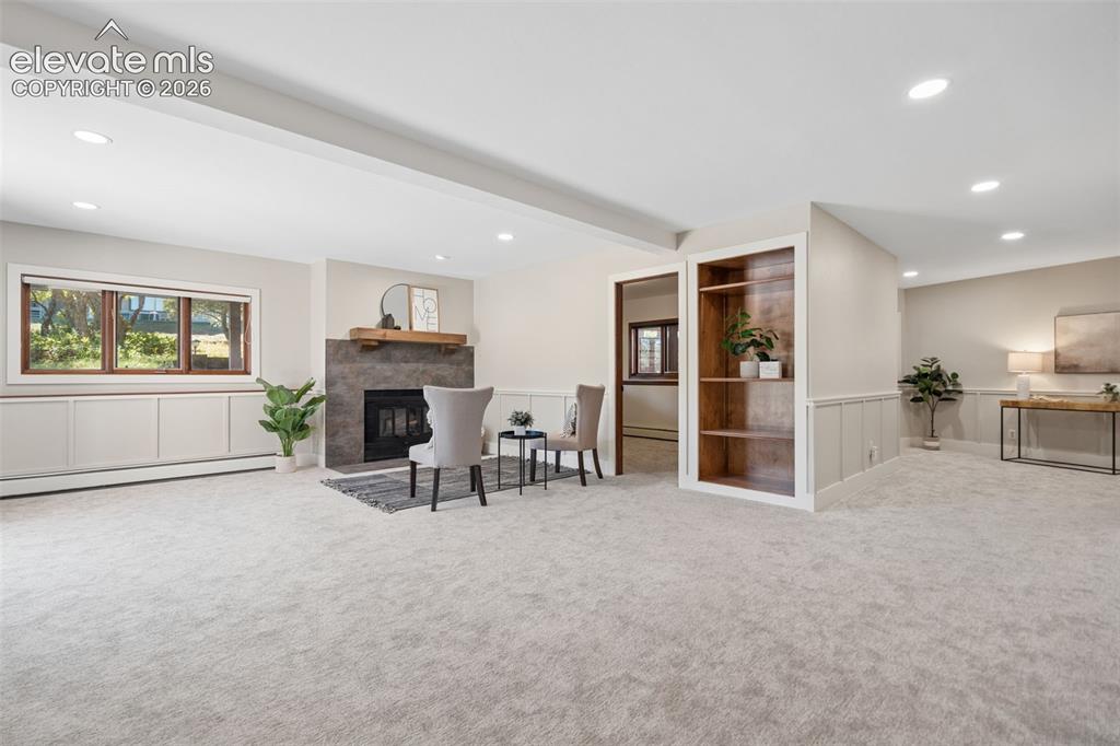 Image 34 of 50: Recessed lighting, built-in shelving, fireplace with stone surround, wainsc