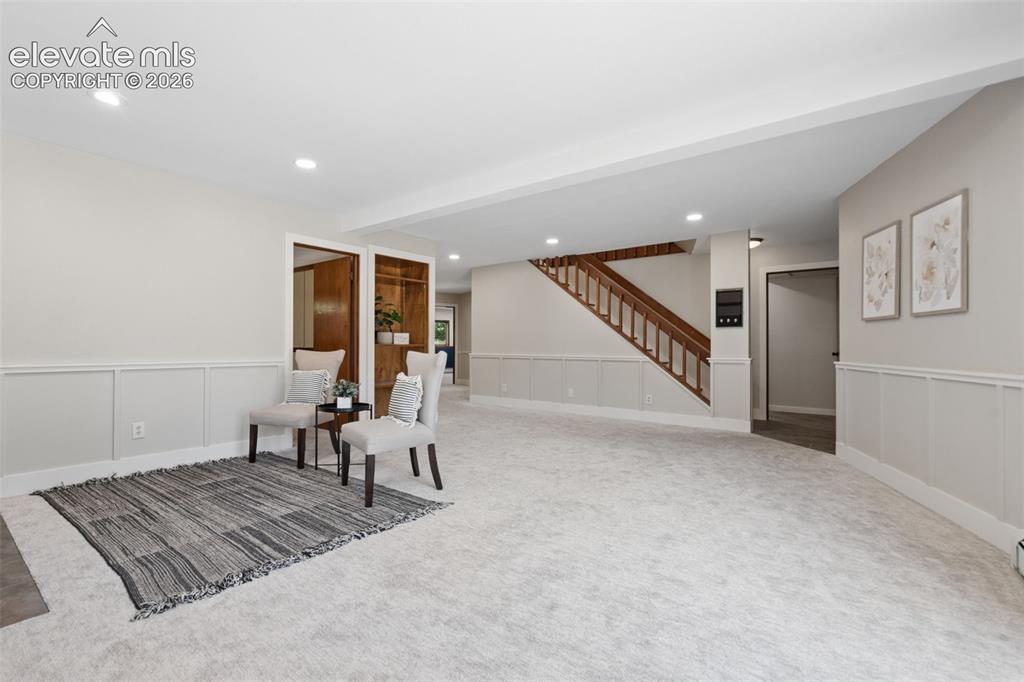 Image 35 of 50: Expansive carpeted room with recessed lighting, wainscoting, and wood-finis