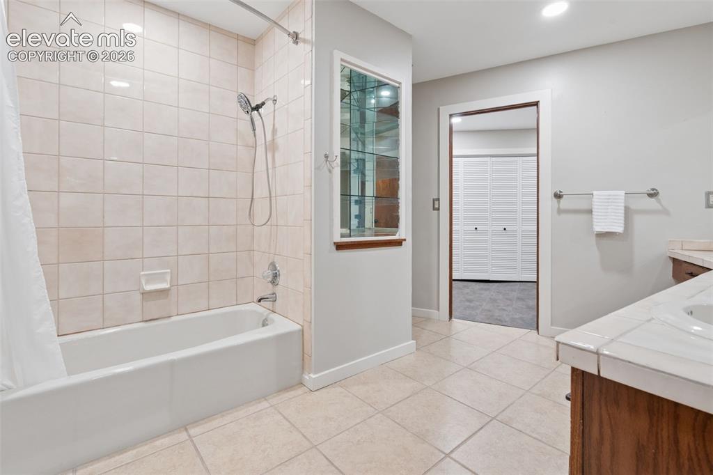 Image 36 of 50: Tile flooring, built-in bathtub with tile surround, recessed lighting, and