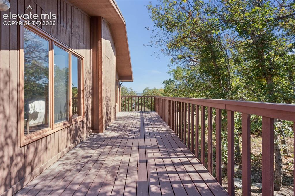 Image 44 of 50: Expansive wood deck with a full-length railing, integrated into the vertica