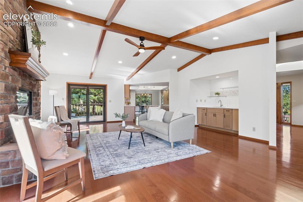Image 5 of 50: Vaulted ceiling with exposed wood beams, stone fireplace with a wood mantle