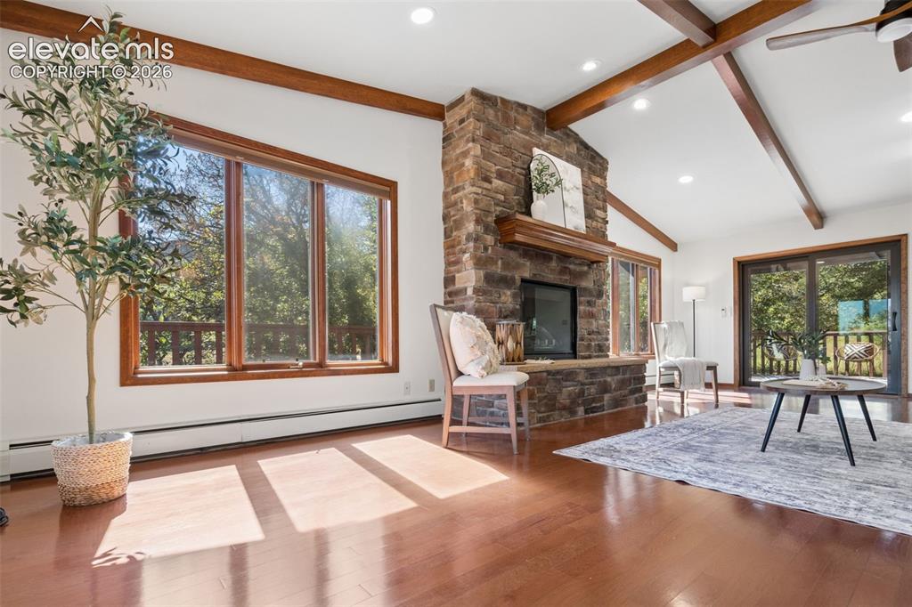 Image 7 of 50: Vaulted ceiling with exposed wood beams, stone fireplace with a wood mantel