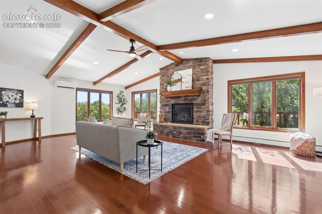 Image 8 of 50: Vaulted ceiling with exposed wood beams, stone-clad fireplace, wood-finish 